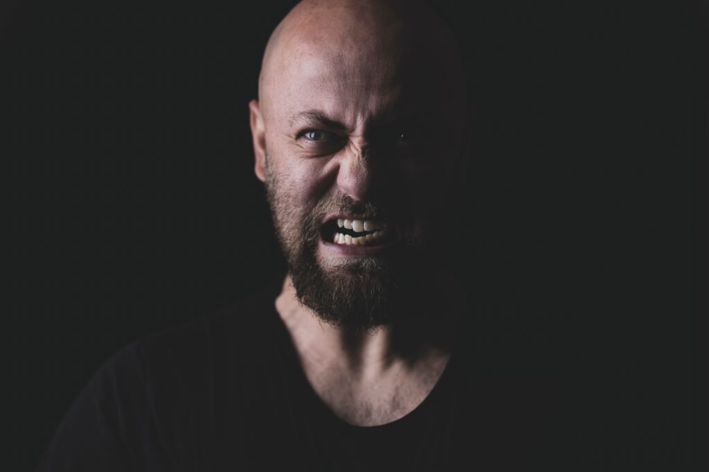 an angry man in shadow with a black background