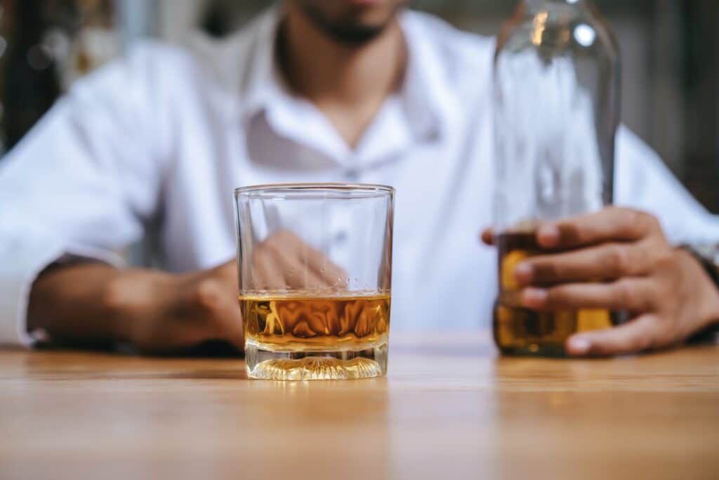 a man having a drink with the bottle mostly empty