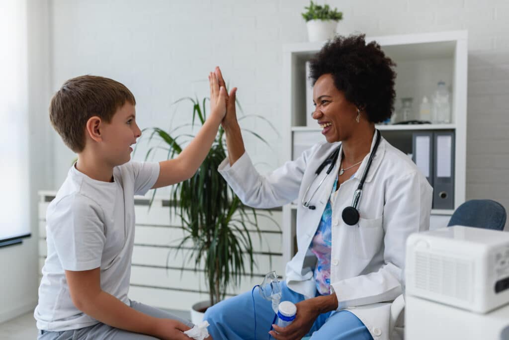 Smiling female doctor general practitioner giving a high five to a child patient