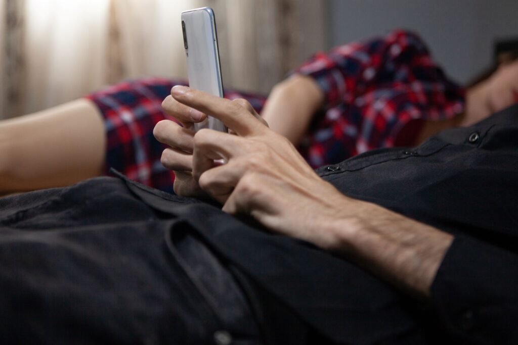 couple laying together while one of them is on the phone